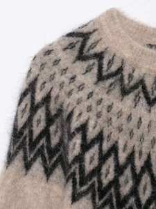 Detail eines weichen Alpaka-Strickpullovers mit schwarzen Fair-Isle-Jacquardmustern