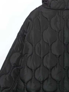 Gros plan sur le matelassage ondulé d'une veste matelassée noire coupe-vent