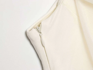 Macro detail of high-quality invisible zipper on a cream-colored woven dress waist