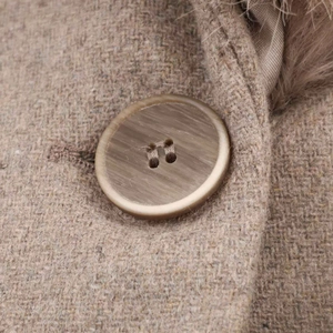 Macro detail of brown tweed wool coat with faux fur collar and wood grain button