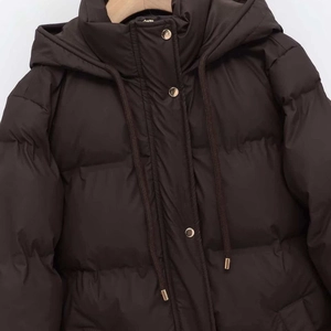 Minimalist dark coffee hooded puffer jacket with metallic gold buttons on wooden hanger