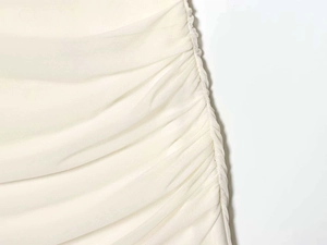 Detail of ruched mesh fabric on a cream white summer dress showing side pleated texture