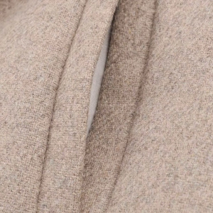Macro shot of oat-colored wool coat showing premium fabric texture and pocket stitching