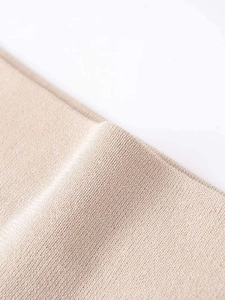 Macro shot of fine knit texture on beige ribbed knitwear showing high-quality fabric details