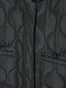 Gros plan d'une veste matelassée noire avec coutures ondulées et cordon de serrage réglable