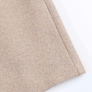 Close-up of oatmeal wool fabric showing premium texture and neat stitching details