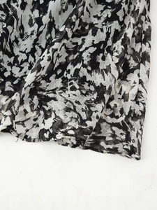 Close-up of printed mini dress featuring abstract monochrome pattern and pleated texture