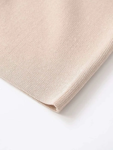 Close-up of beige ribbed knit fabric showing detailed texture and rolled hem edge