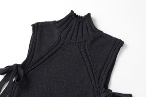 Détail du gilet en maille noire à col montant avec lacets latéraux et texture côtelée