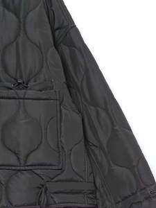 Détail de la veste matelassée noire montrant les coutures et le cordon de serrage réglable