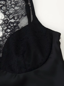 Detailed macro view of black floral lace stitching on silk satin slip dress fabric