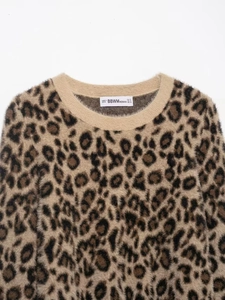 Detail of soft leopard print knit sweater neckline showing ribbed collar and size S tag