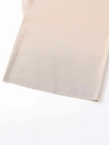 Detail shot of light beige knit fabric showing fine ribbed texture and soft hemline finish