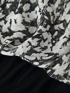 Macro detail showing the contrast between black ink print chiffon and solid black fabric