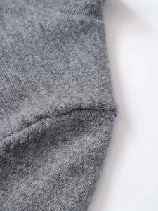 Close-up detail of smooth shoulder seam on grey knit short sleeve high neck sweater