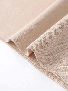 Close-up of beige ribbed knit fabric showing soft texture and high-quality stitching