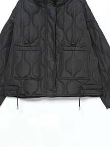 Détail d'une doudoune noire matelassée avec grandes poches à cordon et motif de surpiqûres