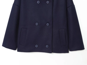 Detail of navy blue wool coat featuring double-breasted buttons and side pockets