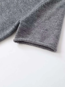 Detail of grey short sleeve knit top showing side slit and rolled hem texture