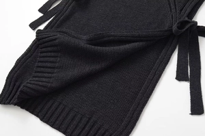 Détail du gilet en maille noire avec lacets latéraux et texture de l'ourlet côtelé