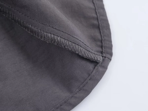 Detailed macro shot of high-quality stitching and dark grey twill fabric on women coat