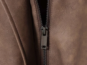 Detail eines grauen Metallreißverschlusses und brauner Wildledertextur an einer Winterjacke