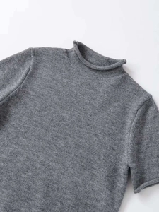 Detailed view of dark grey high-neck knit top showing soft texture and rolled edges
