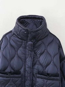 Détail de veste matelassée à col montant et poches à cordon en bleu marine