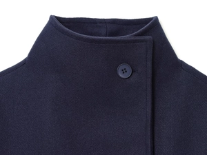 Macro detail of the dark blue wool coat collar featuring a classic round button closure