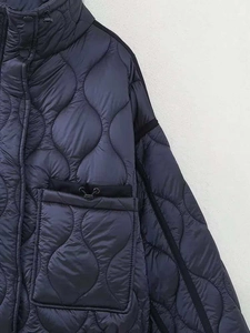 Détail d'une veste matelassée bleu foncé avec col montant et poche à cordon