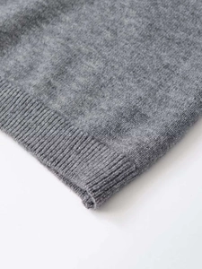 Close-up of gray knit fabric showing the fine texture and ribbed hem detail