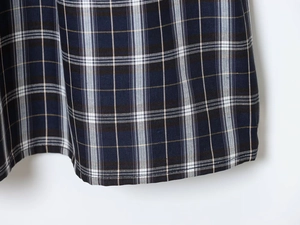 Macro shot of plaid midi skirt hem with blue, brown, and white checkered pattern fabric