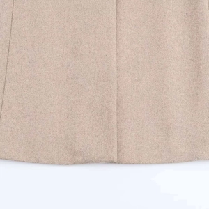 Detail shot of the oatmeal woolen coat hem showcasing thick textured fabric and clean edges