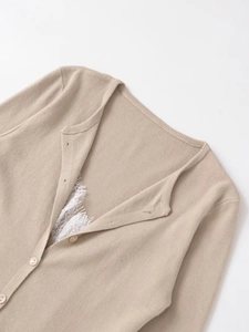 Detailed close-up of beige knit cardigan featuring soft lace trim and round buttons