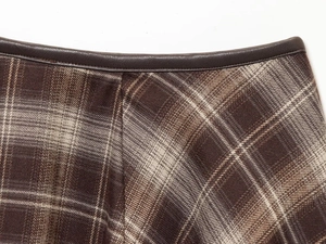 Détail de la taille d'une jupe à carreaux avec bordure en cuir et texture en laine