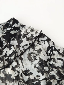 Detail of black and white floral chiffon dress featuring ruffled edges and fine stitching