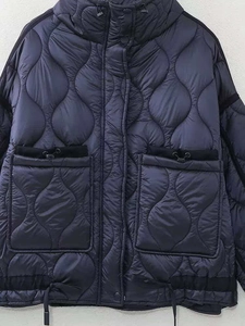 Détail de la veste matelassée bleu marine avec capuche, grandes poches et garnitures