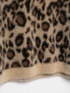Close-up of leopard print faux fur fabric showing dense plush texture and pattern
