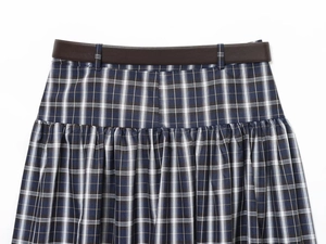 Close-up of blue plaid midi skirt fabric texture with a slim brown leather belt