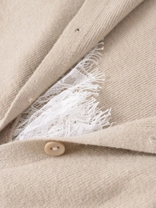 Detail of knit fabric texture with delicate eyelash lace trim and matching button