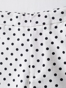Detail of white mini shorts with black polka dots showing waistband and stitching