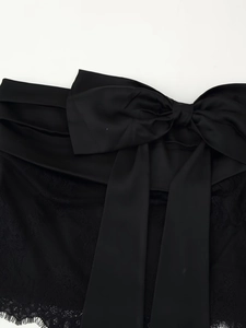 Detail of satin bow and floral eyelash lace on a premium black garment top