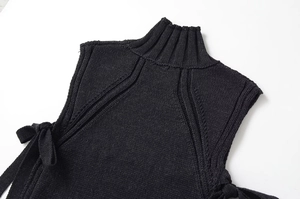 Détail du gilet noir en maille avec col roulé côtelé et motif de tissage vertical texturé