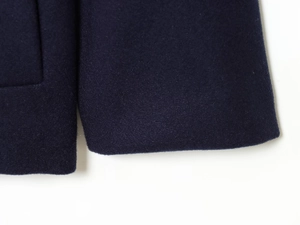 Detailed close-up of navy wool coat fabric showing premium stitching and fine texture
