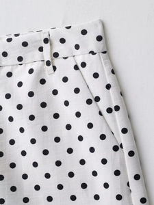 Détail d'un mini-short blanc à pois noirs montrant la texture sergé et les passants de ceinture