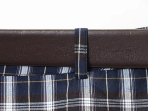 Close-up of vintage plaid midi skirt waist with brown leather detail and fabric belt loops
