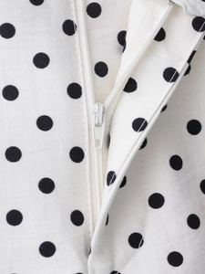 Detail of white nylon zipper and black polka dot fabric with premium stitching