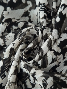 Detailed close-up of pleated black and white floral print fabric with a light chiffon texture