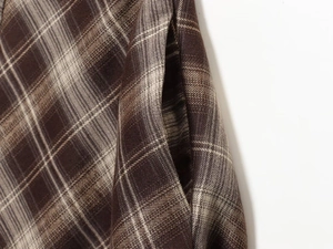 Détail de la poche latérale sur une jupe à carreaux marron en tissu tweed texturé