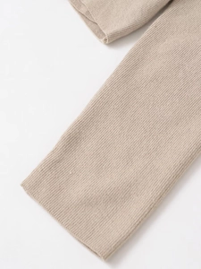 Macro detail of beige ribbed knit texture and elastic cuff finish on a stylish sweater